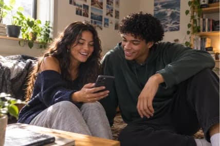 A couple sitting on a sofa, sharing a phone.